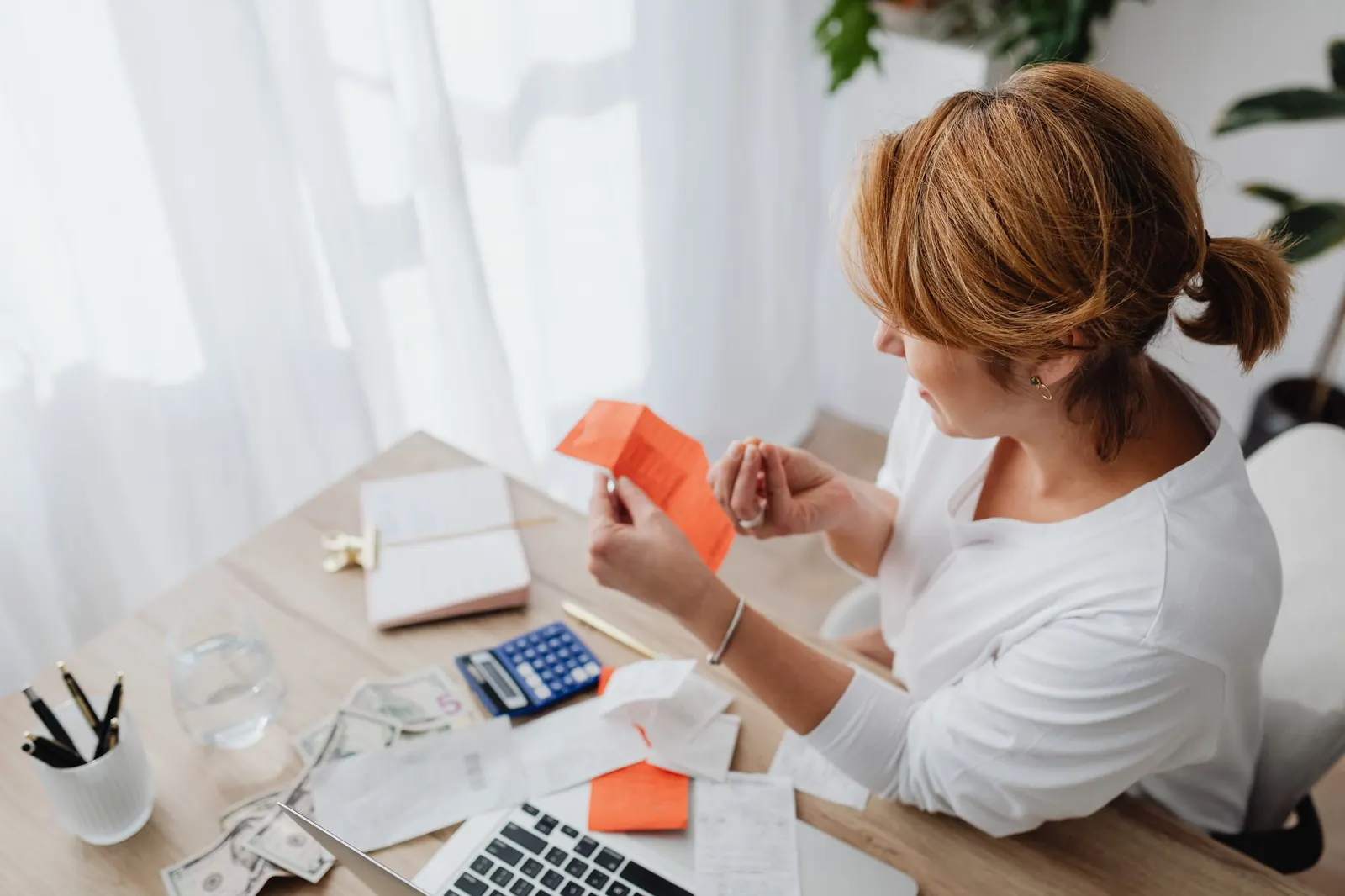 Femme qui range ses factures et son budget devant un ordinateur portable et une calculatrice